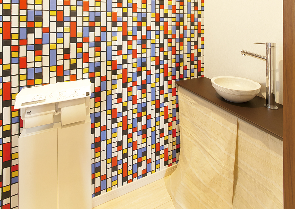 トイレは、居室とは雰囲気を変えてポップなクロスを採用。信楽焼の洗面ボウルが上品さを加えています。