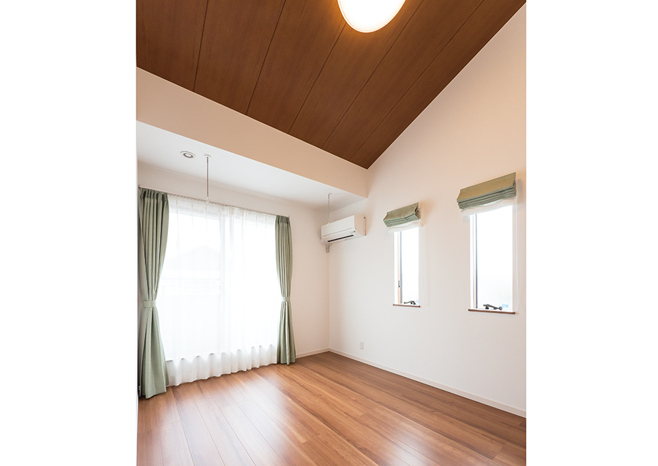 寝室は、床も天井も深みのある色使いで落ち着いた雰囲気にしながら、勾配天井で開放感を出しています。