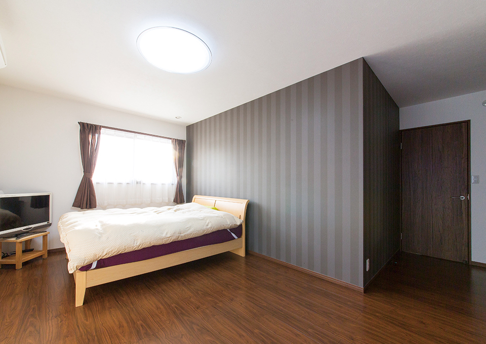 寝室は、深みのある色の床とアクセントウォールで落ち着いた雰囲気にまとめています。
