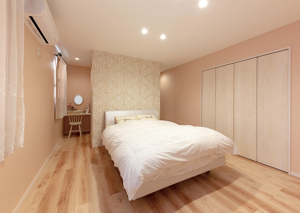淡いピンクの壁に囲まれた寝室は、奥にウォークスルークローゼットを設けています。